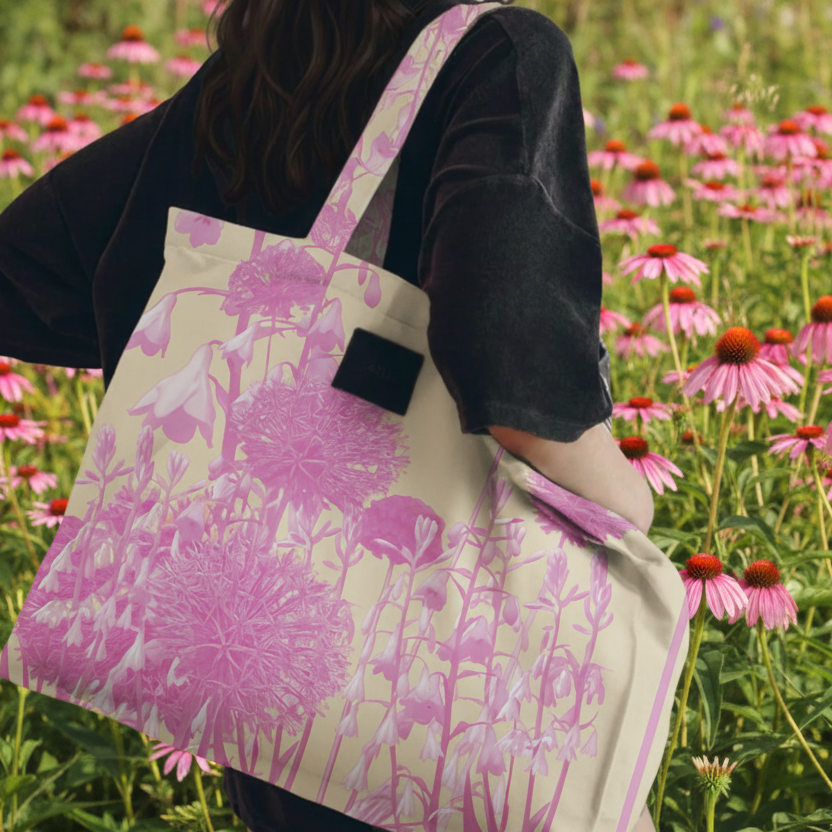 Person holding a tote bag with floral design in a field of flowers