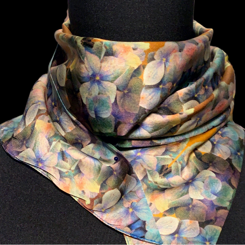 Colorful scarf with abstract pattern worn around a black neck, on a black background