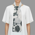 Woman wearing a white shirt with a black and gray patterned scarf on a gray background